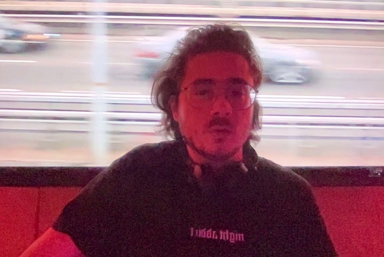 a man with a beard and glasses in front of a tv screen