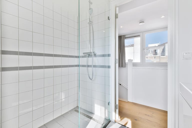 White‑tiled frameless shower, example of a frameless door in a contemporary Auckland bathroom