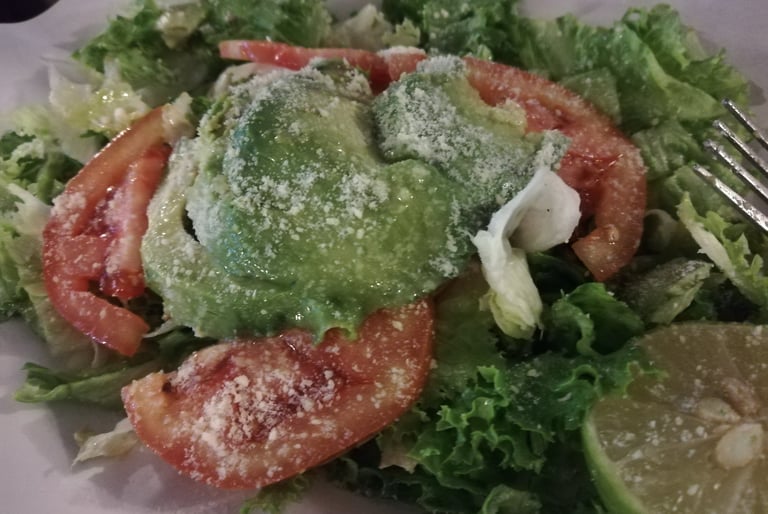 Ensalada fresca con aguacate, jitomate y queso parmesano rallado, la guarnición artesanal ideal para acompañar tus platillos.