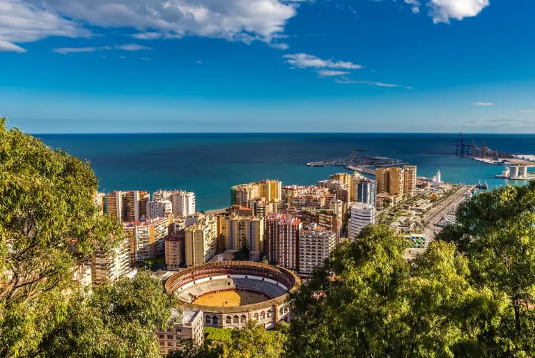 Panoramic aerial view of Malaga city skyline, La Malagueta bullring, and the Mediterranean Sea coast in Spain.
