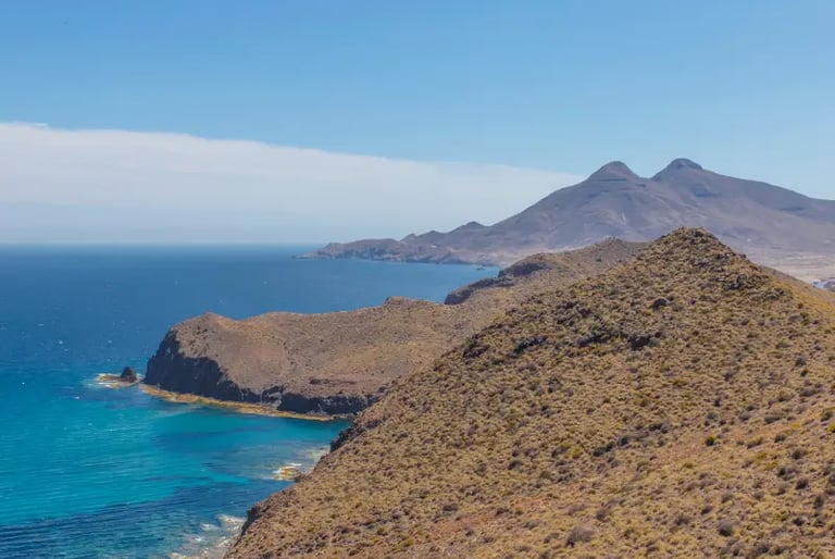 Panoramic coastal view of volcanic cliffs and turquoise water at Cabo de Gata-Níjar Natural Park in Spain.