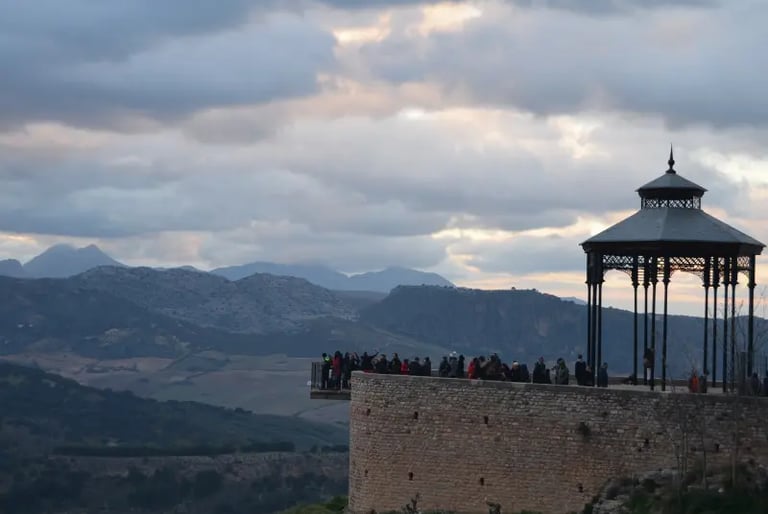 Tourists at the Ronda overlook gazebo enjoying scenic mountain views in Andalusia, Spain.