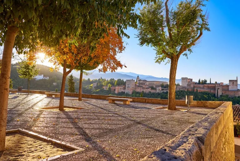 Panoramic view of the Alhambra palace in Granada, Spain at sunset from a cobblestone terrace.