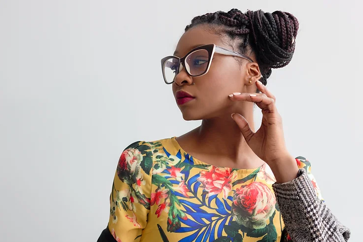 African-American woman with floral print top and hair pulled in a braided bun