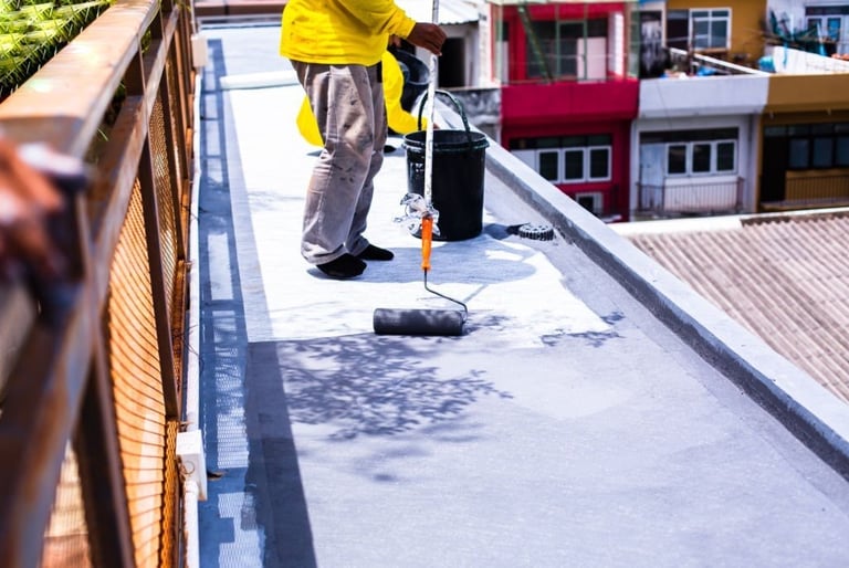 a man in a yellow jacket is painting a roof