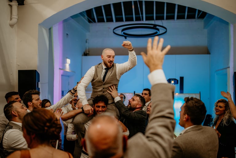 groom celebrating on shoulders having fun at party