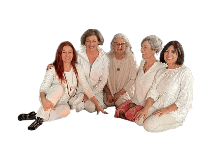 Five smiling senior women posing together in white yoga outfits during a wellness retreat.