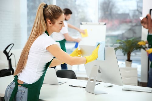 a woman cleaning a computer screen in a room