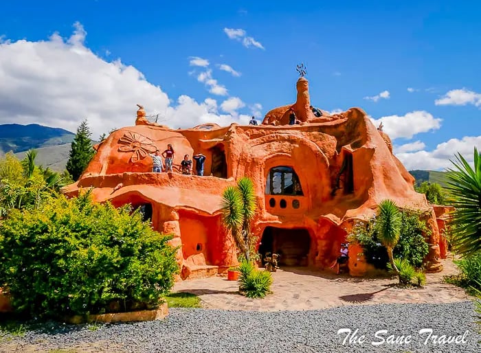 Exterior view of the giant clay Terracotta House with visitors walking on its terraces under a blue sky