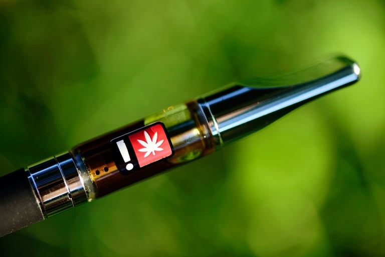 Close-up of a cannabis oil vape cartridge with a THC warning label against a blurred green background.
