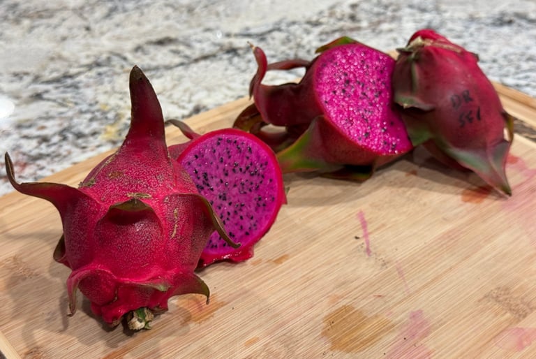 Dragon Fruit, whole and cut open, on a wooden cutting board