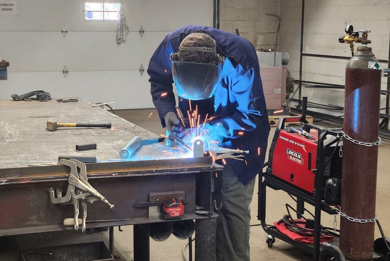 man in welding gear welding a piece of metal