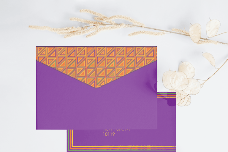 Purple stationery envelope with orange geometric pattern and dried floral accents on white background.