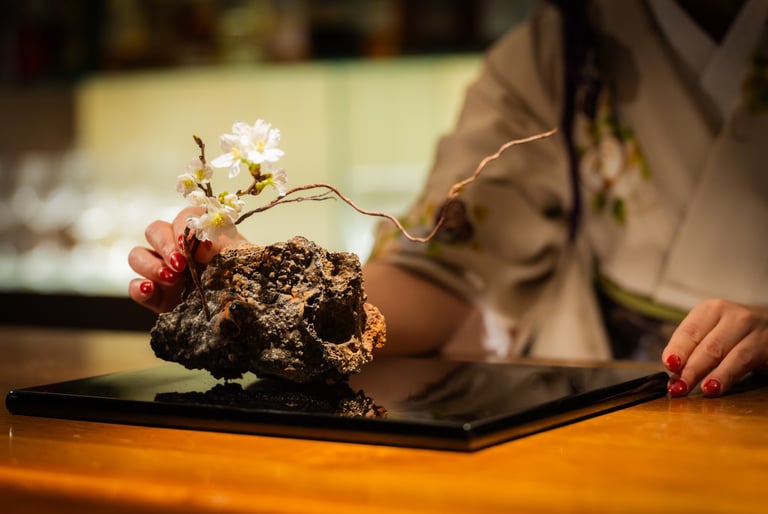 a woman dressed in kimono arranging an ikebana flower arrangement