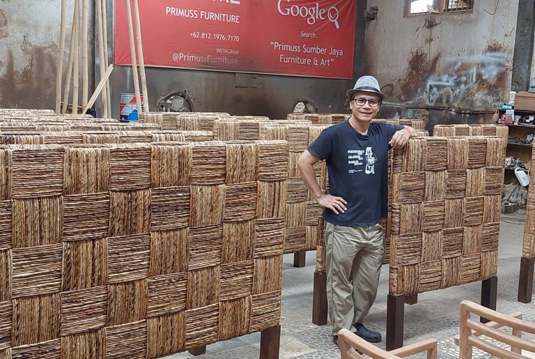 Jiwo standing in front of a large group of headboard weaved by banana fiber