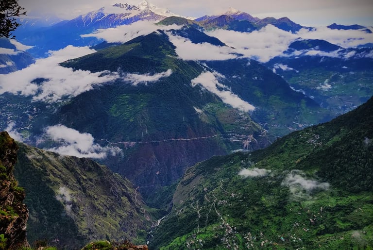 Mountain ridges with clouds and distant snowy peaks.