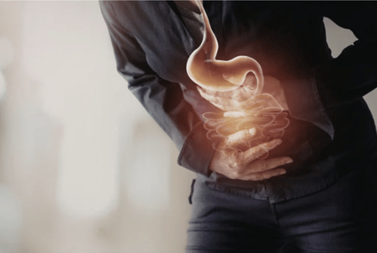 Person clutching abdomen with glowing stomach and intestines illustration showing digestive pain