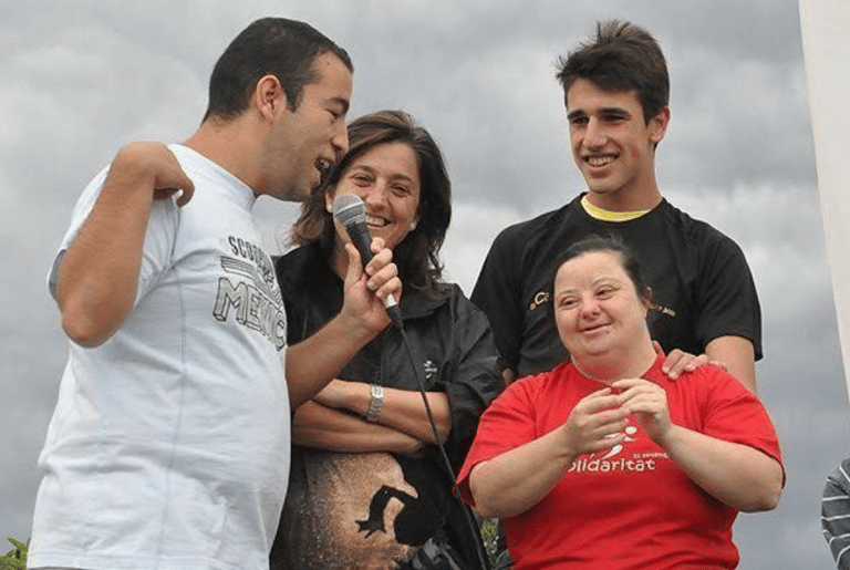 Around Roger Solà, a group of diverse people including woman with Down syndrome in an outdoor event.