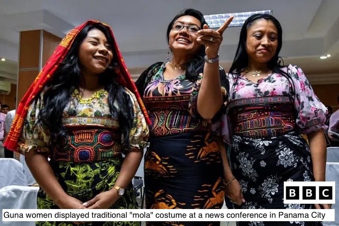 Three Guna women wear colorful traditional mola blouses and skirts at a Panama City conference.