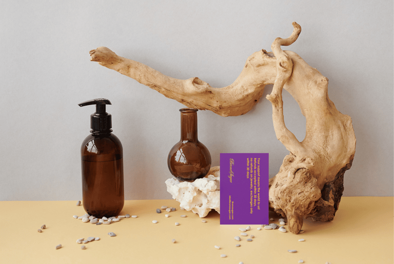Amber glass apothecary bottles and driftwood aesthetic spa branding flat lay with purple card.