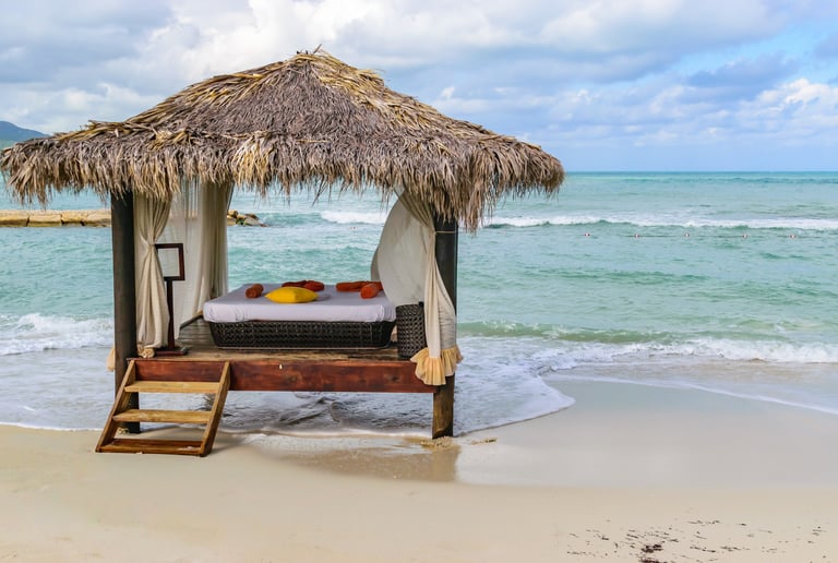 a bed with a canopy over it on the beach next to water
