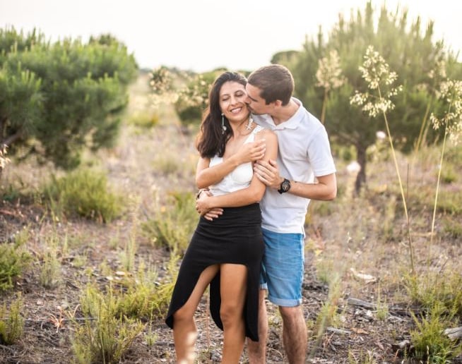 a couple standing in a field with their arms around each other