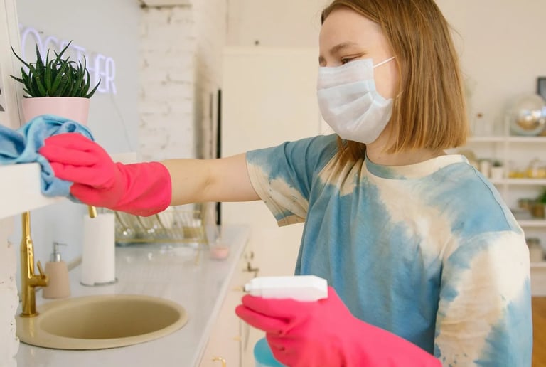 a woman in a mask and gloves is cleaning a sink