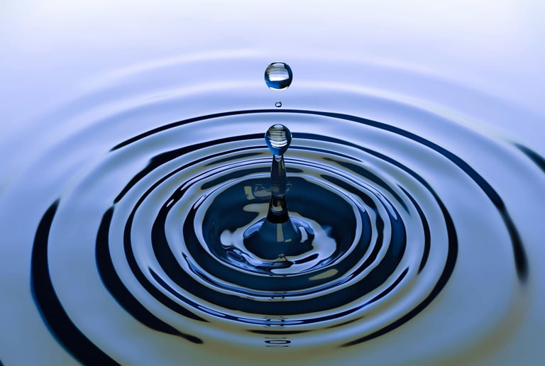 Close-up van waterdruppel die cirkelvormige ringen maakt, symboliseert impact en effect