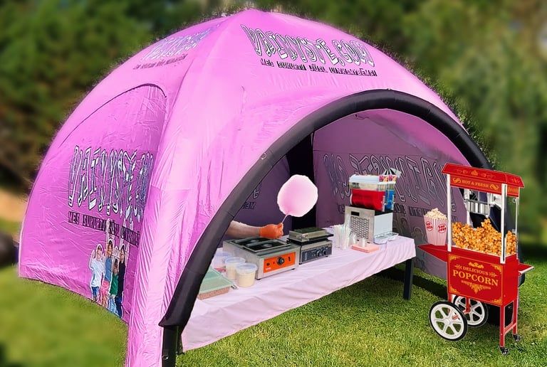 Pink inflatable event tent with popcorn machine and cotton candy station for party rentals.