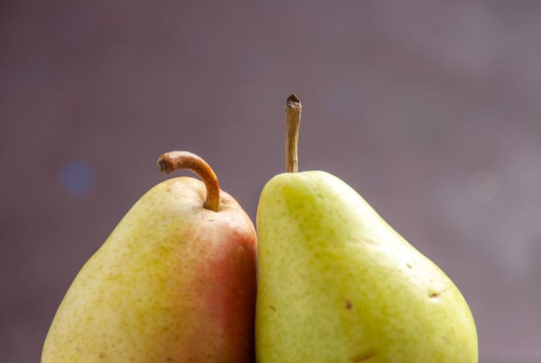 Two fresh organic pears standing on a dark textured surface with a purple background.