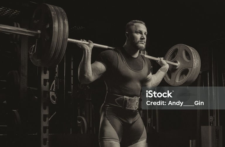 a man holding a barbell in a gym