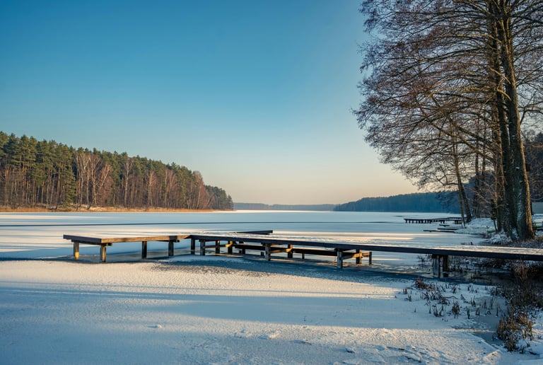 Canadian lake in spring with snow on dock and trees without leaves.