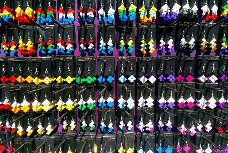 A vibrant display of handmade colorful LEGO earrings hanging on black retail display cards.