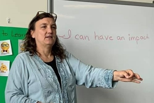 Leah Kyaio in front of a white board that reads "I an have an impact."
