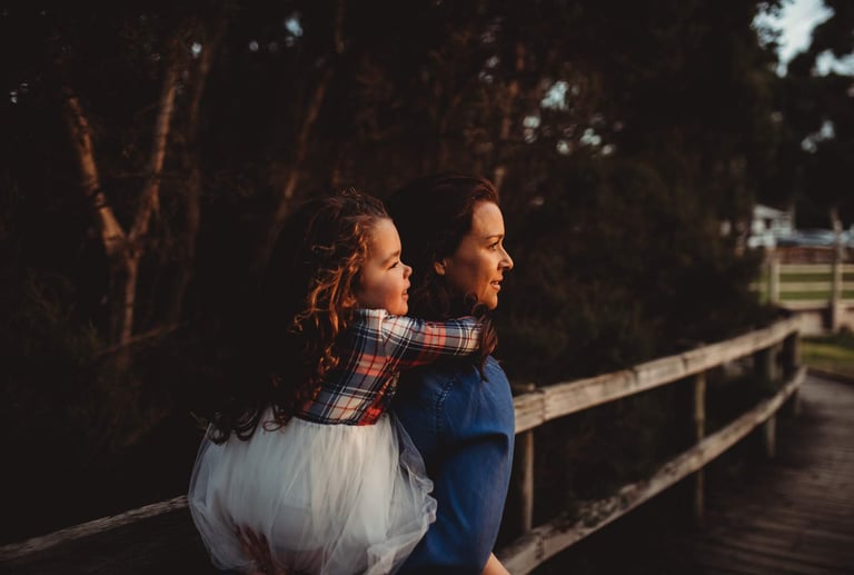a young girl riding on a womans back on a wooden bridge