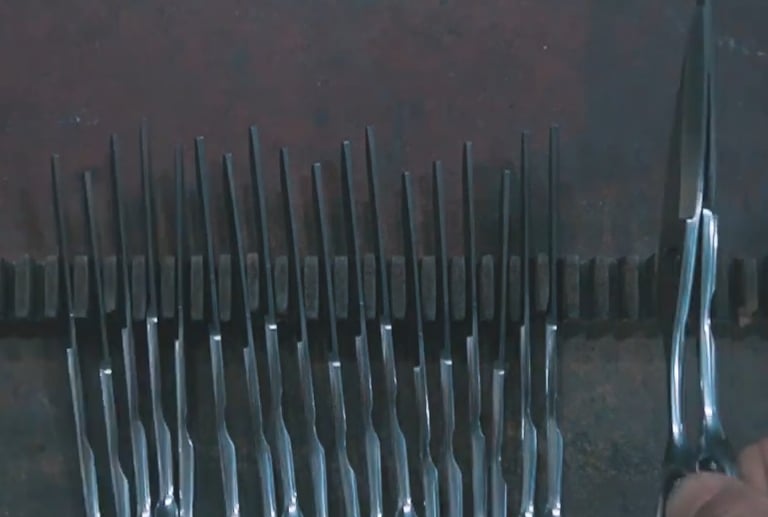 Tijeras profesionales de peluquería fabricadas y alineadas en fila; producción y control de calidad.