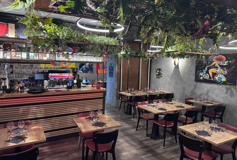 Modern restaurant interior featuring a stylish bar, wooden tables, and lush hanging plants.