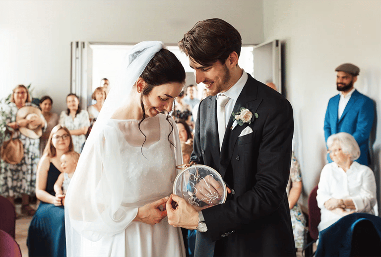 Échange des alliances lors du mariage civil de Bérengère et Nicolas, entourés de leurs proches.
