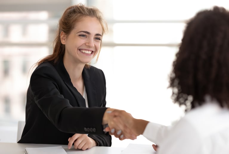 a woman in a business suit shaking hands with a man in a suit