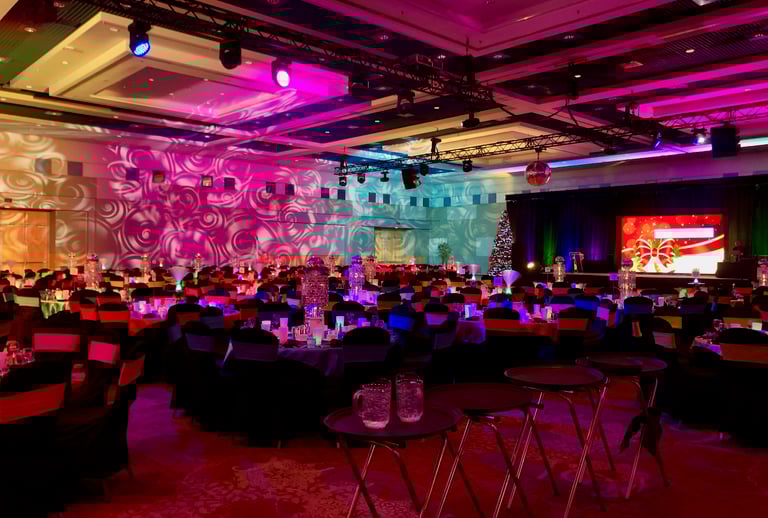A corporate holiday party featuring lots of audiovisual gear at a convention centre in a ballroom.