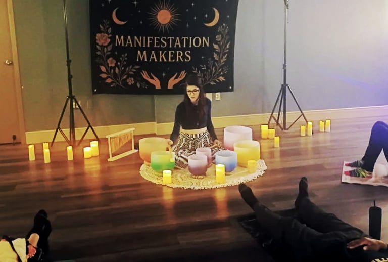 Woman playing crystal singing bowls with people laying around her