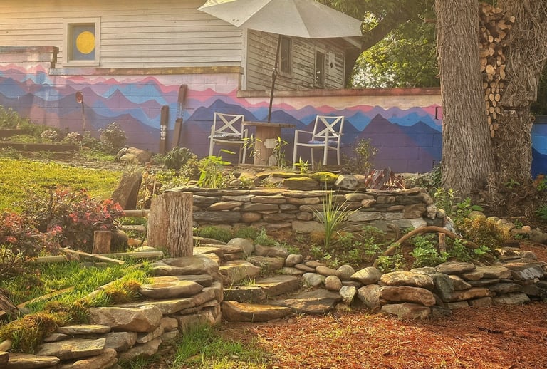 a garden with a stone wall and a patio umbrella