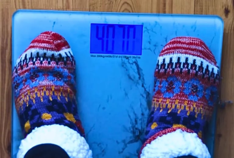Feet standing on a weight scale representing weight loss moderation journey