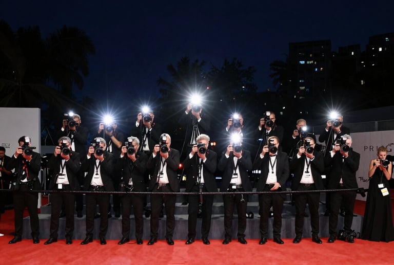 A wide-angle shot of a premiere red carpet event at night. The flashes of cameras create a sparkling light effect against the dark navy night sky. A sense of prestige, stardom, and modern cinematic luxury.