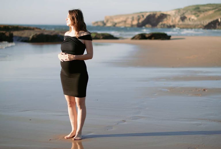a pregnant woman standing on a beach