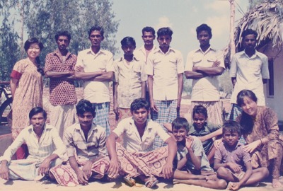 Kayoko standing on the left of 14 Kalamkari artists. some standing and some sitting.