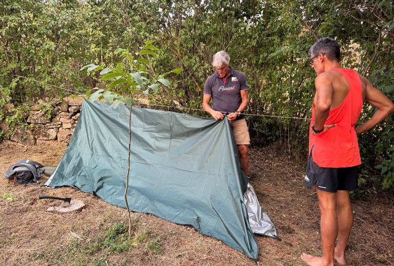 dos personas construyendo un refugio de fortuna con un tarp suspendido de una linea de cordino