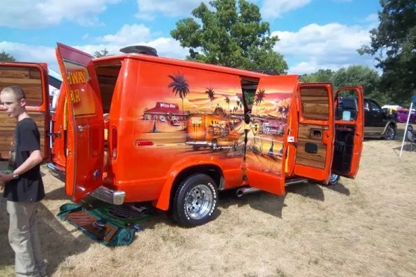 a man standing next to a van with a surfboard