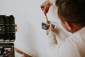 a man is fixing a light switch on a wall
