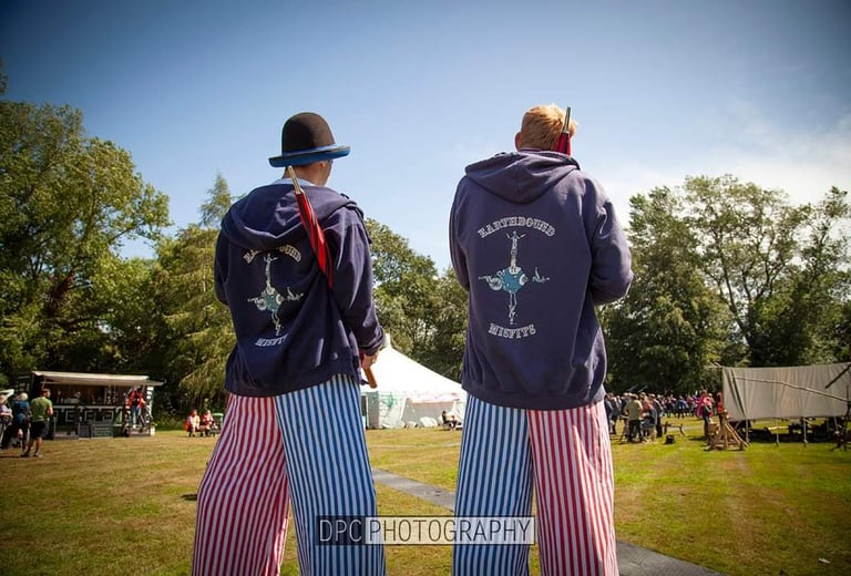Two performers in striped pants and branded hoodies entertain crowds at an outdoor festival.